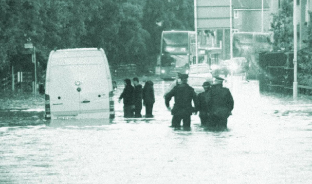 Police and residents wading through flooding in Newham 2021, where a white van is semi-submerged in the water
