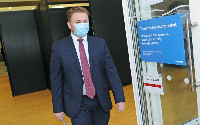 A man in a suit wearing a face mask leaving the testing centre