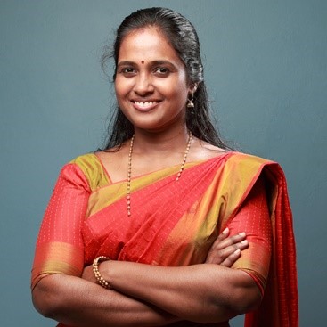 Young woman wearing orange and gold sari smiling to camera