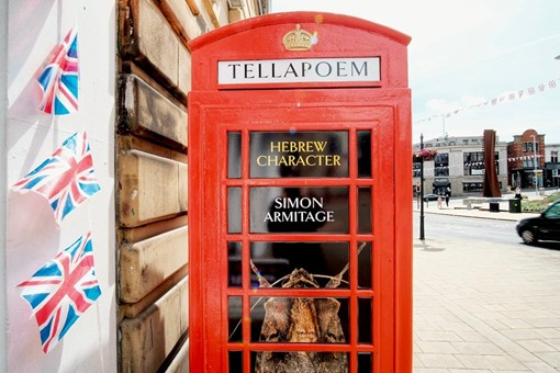  A traditional red telephone box with a window vinyl containing the words Hebrew Character, Simon Armitage and a picture of a moth (relating to the poem) 