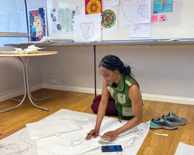 A young girl taking part in a creative workshop drawing on a large piece of paper