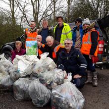 Older volunteers litter picking with large bags of rubbish