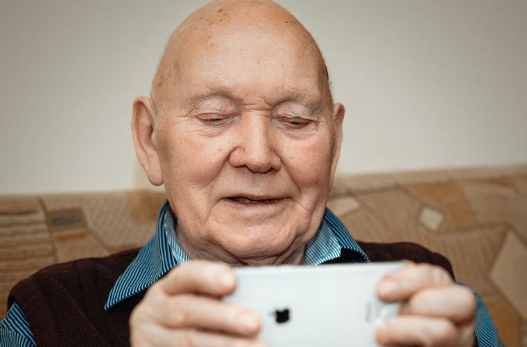 Elderly man sitting on a sofa holding at an i-phone