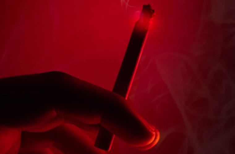 Hand holding a cigarette under a red light