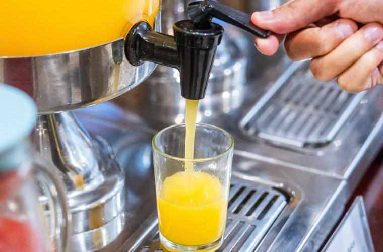 Hand operating a juice machine in a coffee shop