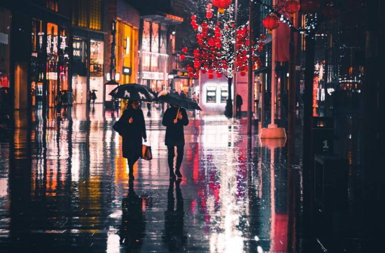 Two women walking down a rainy street at night