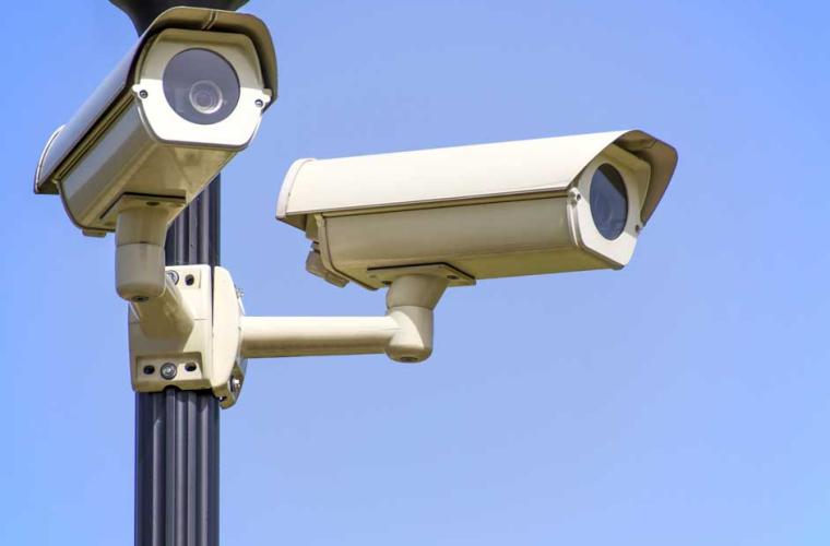 two cctv cameras in front of a blue sky