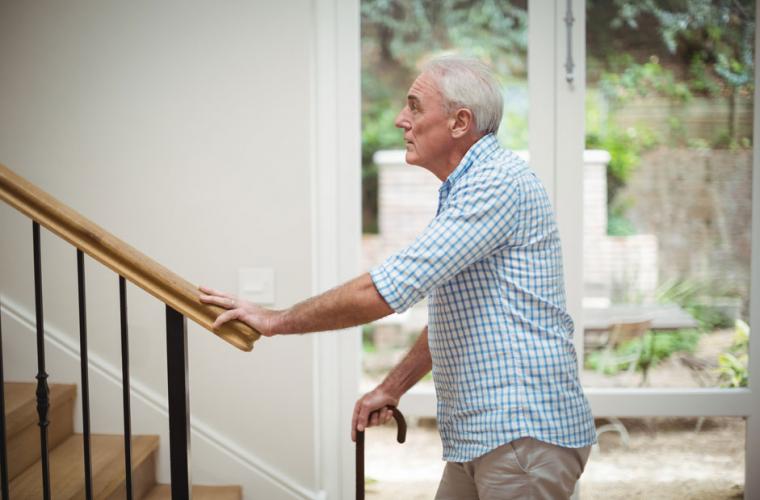 photo of old man with walking stick about to climb stairs